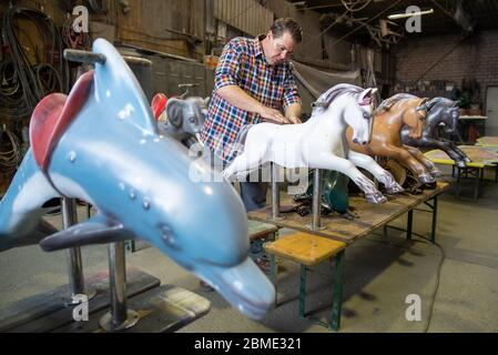 28 avril 2020, Bavière, Burgthann : le showman Johannes Braun polit les figures du carrousel dans son atelier. Il a été habitué à être un showman depuis qu'il était un enfant. Braun dirige l'entreprise familiale de la 7e génération avec sa mère. En fait, Johannes Braun et sa famille sont sur la route depuis des mois. Avec des voitures tamponneuses et un carrousel pour enfants, ils voyagent de la foire à la foire. Mais en raison de la crise de la couronne, Braun est actuellement incapable de travailler et craint maintenant pour son existence. (À dpa 'réparations et stand de bonbons au lieu de l'agitation du parc d'expositions') photo: Daniel Karmann/dpa Banque D'Images