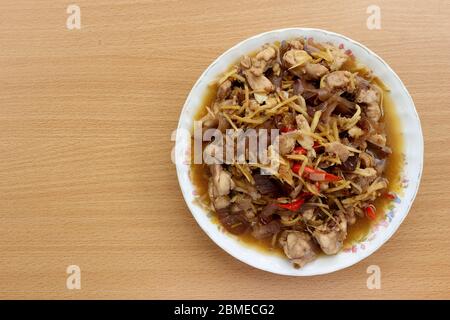 Vue de dessus. Faire sauter le poulet avec du gingembre composé de champignons, d'ail, de poivrons frais placés sur une assiette et sur un fond en bois. Banque D'Images