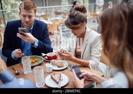 Jeunes gens occasionnels à déjeuner d'affaires message texte. Banque D'Images