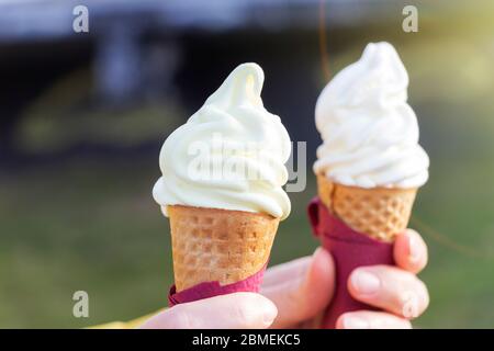 Woman's hands holding melting ice cream cornet gaufré dans les mains sur la lumière d'été nature background Banque D'Images