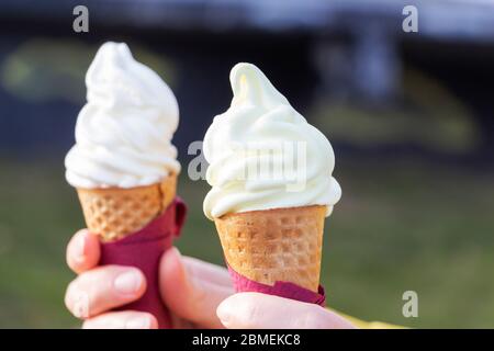 Woman's hands holding melting ice cream cornet gaufré dans les mains sur la lumière d'été nature background Banque D'Images