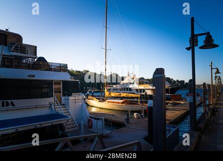 Un vieux yacht classique en bois pris par le soleil entouré de nouveaux bateaux à moteur Banque D'Images