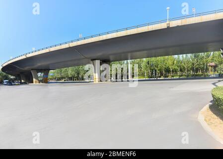 Sous le pont, route asphaltée sans voiture, gratte-ciel moderne de construction de ville comme arrière-plan. Banque D'Images