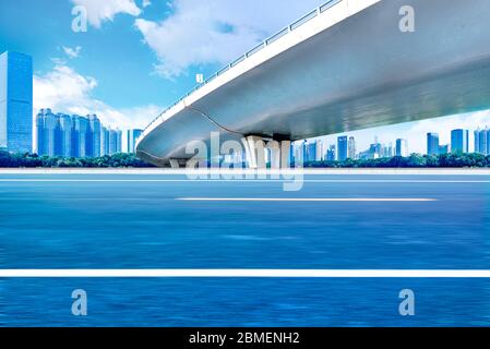 Sous le pont, route asphaltée sans voiture, gratte-ciel moderne de construction de ville comme arrière-plan. Banque D'Images