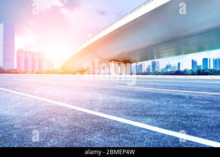 Sous le pont, route asphaltée sans voiture, gratte-ciel moderne de construction de ville comme arrière-plan. Banque D'Images