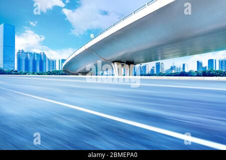 Sous le pont, route asphaltée sans voiture, gratte-ciel moderne de construction de ville comme arrière-plan. Banque D'Images