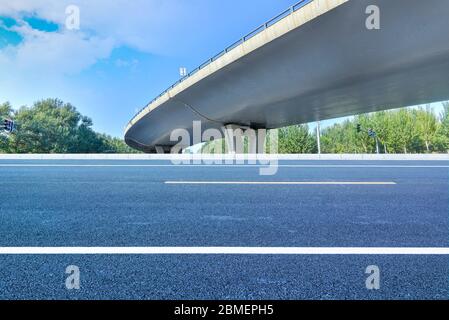 Sous le pont, route asphaltée sans voiture, gratte-ciel moderne de construction de ville comme arrière-plan. Banque D'Images