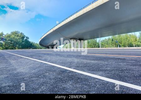 Sous le pont, route asphaltée sans voiture, gratte-ciel moderne de construction de ville comme arrière-plan. Banque D'Images