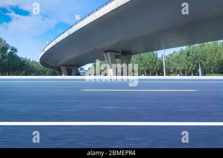 Sous le pont, route asphaltée sans voiture, gratte-ciel moderne de construction de ville comme arrière-plan. Banque D'Images