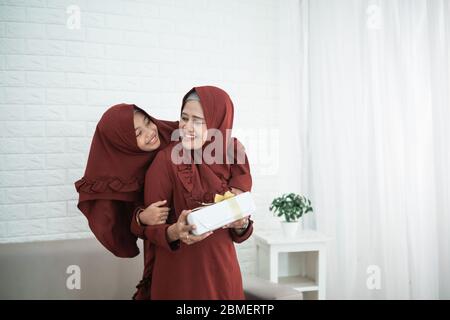 La fille embrasse et donne des cadeaux à sa mère lors de la célébration de l'Eid heureux Banque D'Images