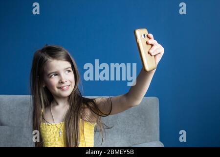 fille prend un selfie sur son téléphone dans une pièce avec des murs bleus Banque D'Images