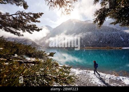 Sac à dos et appareil photo touristique avec marche dans la neige à la plage du lac de montagne au Kazakhstan, en Asie centrale Banque D'Images