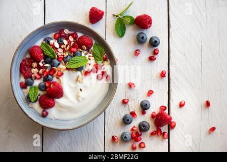 Yaourt avec fruits frais, menthe et céréales dans un bol, petit déjeuner sain Banque D'Images