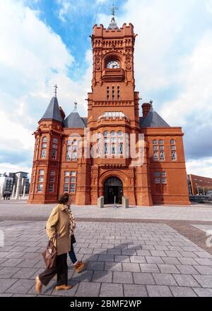 Cardiff, pays de Galles, Royaume-Uni - 17 mars 2013 : des piétons marchent le long du bâtiment victorien orné Pierhead dans la baie de Cardiff. Banque D'Images