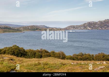 Torridon, Écosse, Royaume-Uni - 24 septembre 2013 : un navire accoste dans le Haut Loch Torridon pour servir une ferme de saumon, sous la côte accidentée du Harg du Nord-Ouest Banque D'Images