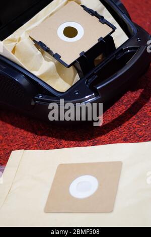 Un aspirateur avec un jeu de brosses et de sacs. Un aspirateur sur le tapis rouge. Banque D'Images