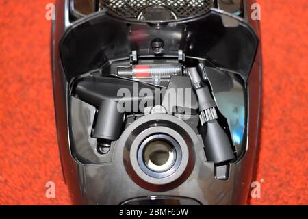 Un aspirateur avec un jeu de brosses et de sacs. Un aspirateur sur le tapis rouge. Banque D'Images