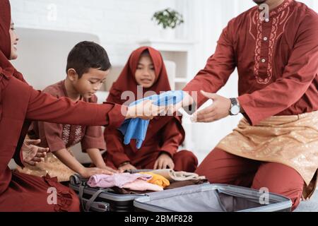 La famille asiatique prépare des vêtements et met dans une valise pour être amené mudik à la ville natale Banque D'Images