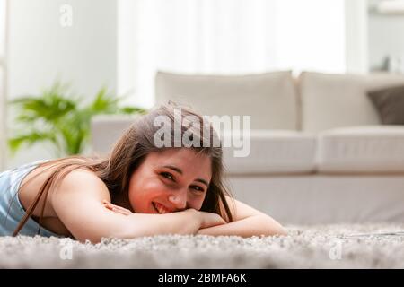 Souriante, une jeune femme heureuse, couchée sur son lit, se détendant et se détendant dans une vue en angle bas au niveau de son lit Banque D'Images