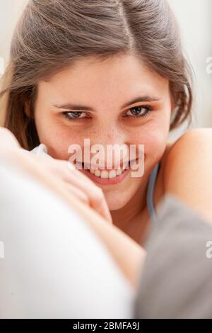 Jolie jeune fille avec un sourire chaleureux et agréable se détendre sur un canapé à la maison dans un portrait de gros plan Banque D'Images