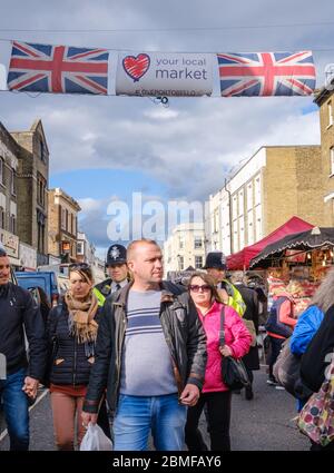 Touristes et Londoniens font leurs courses au marché de Portobello. Une bannière de rue au-dessus de laquelle vous avez deux prises Union & a Heart vous dit votre marché local. Portobello Road, Londres Banque D'Images