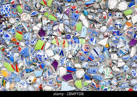 Gros plan sur un mur, décoré de morceaux cassés de pots faits main en céramique. Texture et arrière-plan très colorés. Banque D'Images