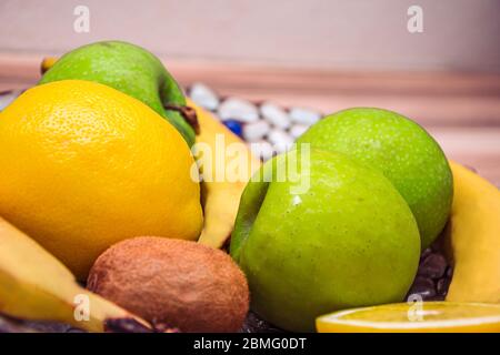 Gros plan de pomme, de citron et d'autres fruits dans un bol sur la table Banque D'Images