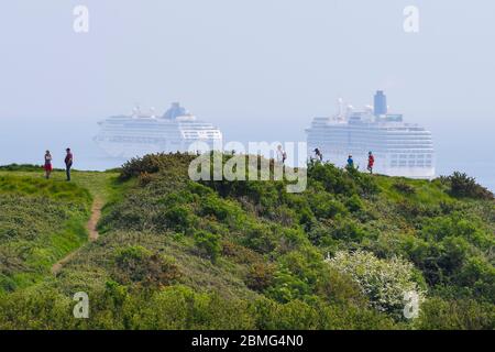 Weymouth, Dorset, Royaume-Uni. 9 mai 2020. Météo au Royaume-Uni : Marcheurs au sommet de la falaise sur le South West Coast Path avec vue sur les cinq bateaux de croisière ancrés dans la baie au large de la côte de la station balnéaire de Weymouth à Dorset, par une chaude journée ensoleillée en raison de la fermeture de l'industrie de croisière pendant le confinement du coronavirus. Il y a quatre navires P&O qui sont les Oceana, Aurora, Arcadia et Ventura et un navire Cunard le navire de ligne Queen Mary 2. (Oceana et Arcadia en photo) photo : Graham Hunt/Alay Live News Banque D'Images