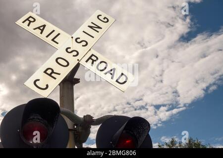 panneau de signalisation blanc et arrière indiquant le passage à niveau de la route ferroviaire avec de grandes lumières rouges le jour de l'été Banque D'Images