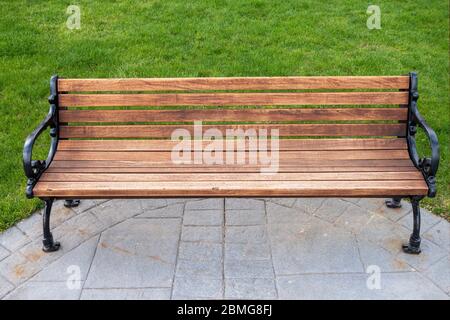 parc boisé et banc classique en fonte noire avec pelouse verte et passerelle en ciment Banque D'Images