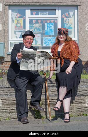 Les résidents locaux Tony Mitchell, vêtus de Winston Churchill, présentent une copie originale du journal Daily Mirror à la petite-fille Carys Banque D'Images