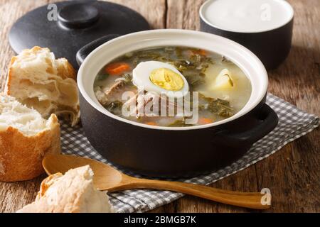 portion de borsch vert de l'ostréiche, légumes, œufs avec viande dans une casserole, servi avec du pain et de la crème sure sur la table. horizontale Banque D'Images