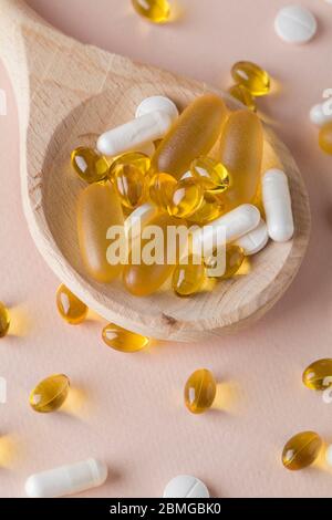 Vitamines et suppléments naturels sur des cuillères en bois sur fond rose. Vue du dessus plat de poser à la verticale Banque D'Images