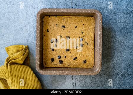 Tranches de gâteau d'avoine biologique et saine, avec banane et copeaux de chocolat dans un moule à gâteau carré. Dessert bio. Banque D'Images