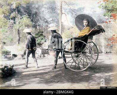 [ 1880 Japon - une femme japonaise en pousse-pousse ] — UNE femme tenant un parasol est assise dans un pousse-pousse. photographie d'albumine vintage du xixe siècle. Banque D'Images