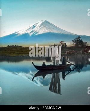 [ 1900s Japon - Mont Fuji ] — VUE sur un Mont Fuji enneigé vu du lac Kawaguchi dans la préfecture de Yamanashi. Devant se trouve un petit voilier. Texte original: 'Maintenant coiffé Fuji vu du lac Kawaguchi.' diapositive en verre vintage du xxe siècle. Banque D'Images