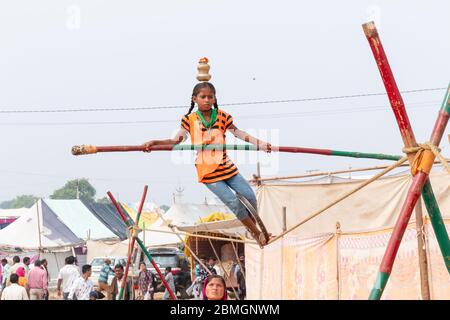 Jeune fille exécutant acrobaties dans corde serrée et l'équilibrage avec bambou à la Foire de Pushkar Banque D'Images