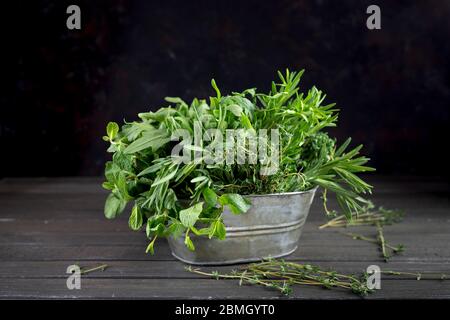 Mélange frais et parfumé d'herbes vertes sur fond de bois foncé dans un bol en métal. Thym romarin basilic coriandre, épinards à la menthe poivrée, salade, arugula. Zéro Banque D'Images