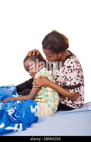 femme inquiète prend la température de son fils malade sur le lit et pleurer dans la douleur Banque D'Images
