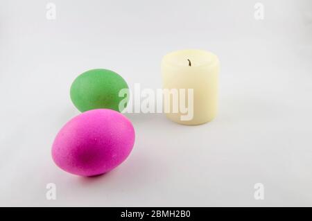 Quelques oeufs de pâques, avec une bougie blanche de pâques, isolés sur fond blanc, colorés par lapin de pâques Banque D'Images