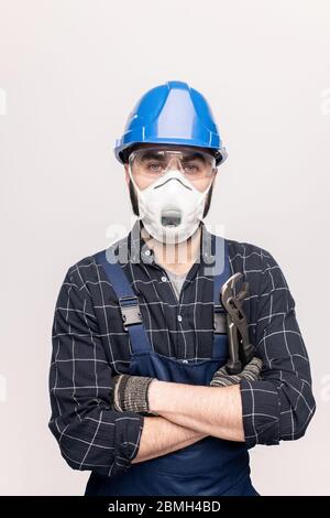 Ingénieur ou réparateur armé en vêtements de travail, gants de protection, lunettes et masque respiratoire debout devant la caméra Banque D'Images