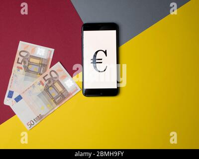 Madrid, Espagne - Mai, 2020 Euro iPhone écran d'application avec de l'argent sur fond de papier coloré. Banque D'Images