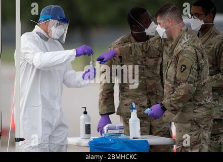 SPC. Nicholas Cisneros passe un écouvillon nasal prélevé sur un patient pendant que l'équipe mobile de test de la Garde nationale du Texas (MTT) teste le coronavirus dans une clinique de conduite gratuite dans la petite ville de Taylor, au centre du Texas. Banque D'Images