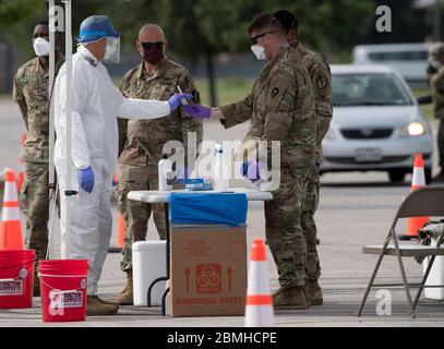 SPC. Nicholas Cisneros passe un écouvillon nasal prélevé sur un patient pendant que l'équipe mobile de test de la Garde nationale du Texas (MTT) teste le coronavirus dans une clinique de conduite gratuite dans la petite ville de Taylor, au centre du Texas. Banque D'Images