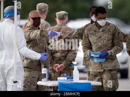 SPC. Nicholas Cisneros passe un écouvillon nasal prélevé sur un patient pendant que l'équipe mobile de test de la Garde nationale du Texas (MTT) teste le coronavirus dans une clinique de conduite gratuite dans la petite ville de Taylor, au centre du Texas. Banque D'Images