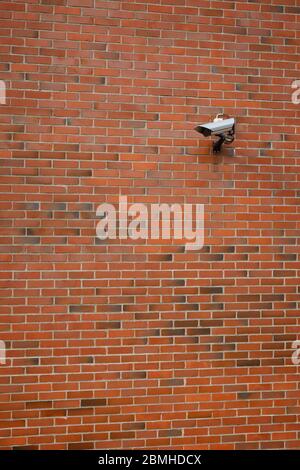 Caméra de vidéosurveillance montée sur un mur en brique rouge. Banque D'Images