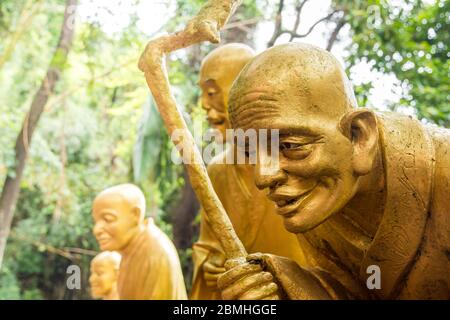 Assis des statues dorées au temple bouddhiste des dix mille bouddhas à Pai Tau, New Territories, Hong Kong Banque D'Images