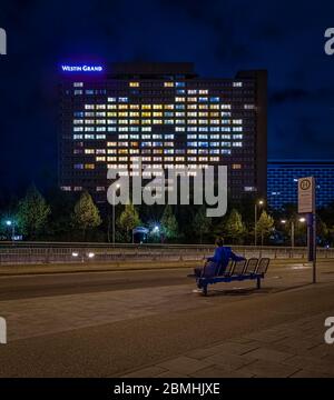 Homme assis sur un banc et regardant les fenêtres illuminées en forme de cœur de l'hôtel Grand Westin de Munich. L'Allemagne au 14 avril 2020 symbolise Banque D'Images