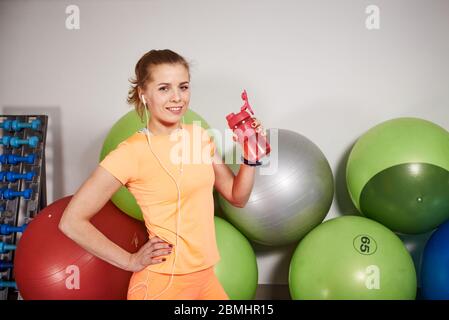 Jeune femme sportive et mince avec bouteille d'eau au club de fitness. Banque D'Images