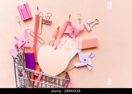 Papeterie et autocollants sur fond rose dans un panier. Fournitures de bureau pour l'école. Banque D'Images